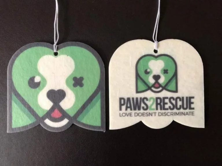 A photo of two sides of a Paws2Rescue branded car air freshener with muted green colours.