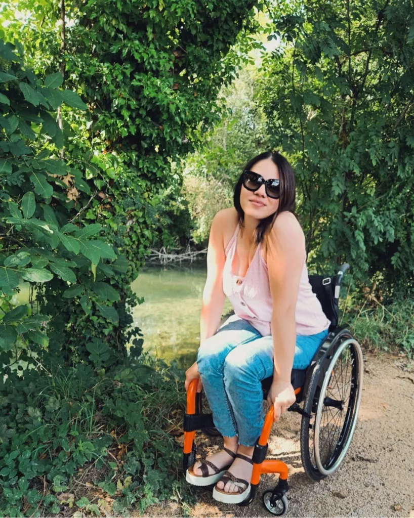 Roxanna pictured sitting in a wheelchair in a beautiful grassy area